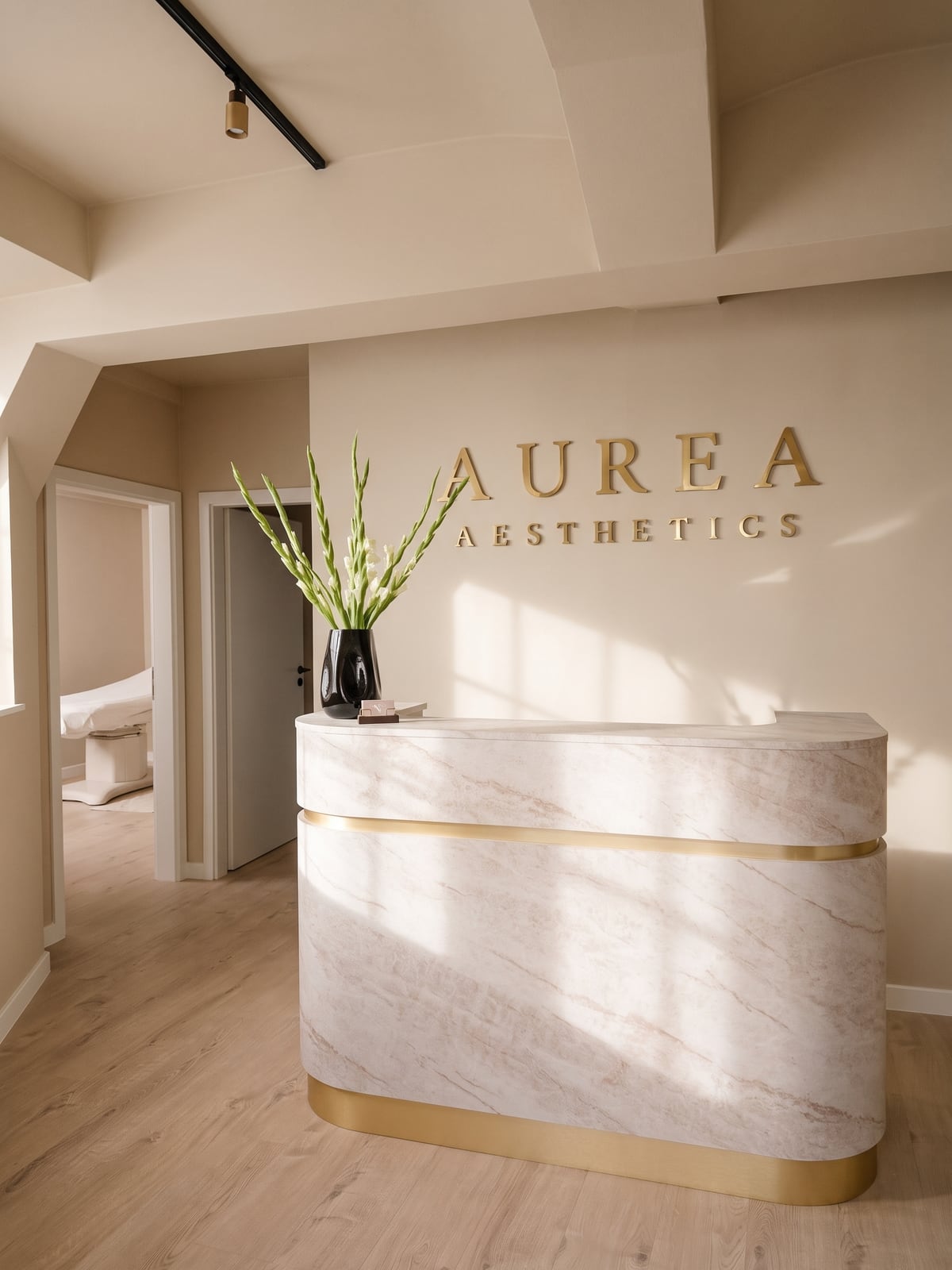 Empfang von Aurea Aesthetics mit Marmortresen, weißen Gladiolen und goldenem Schriftzug